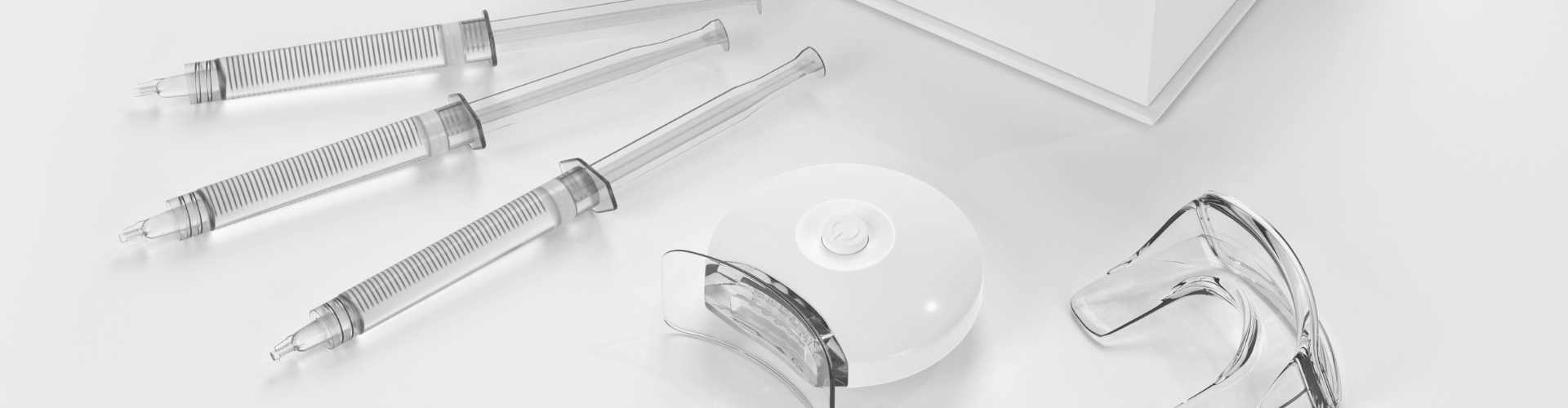 Teeth-whitening kit on white surface with white box.